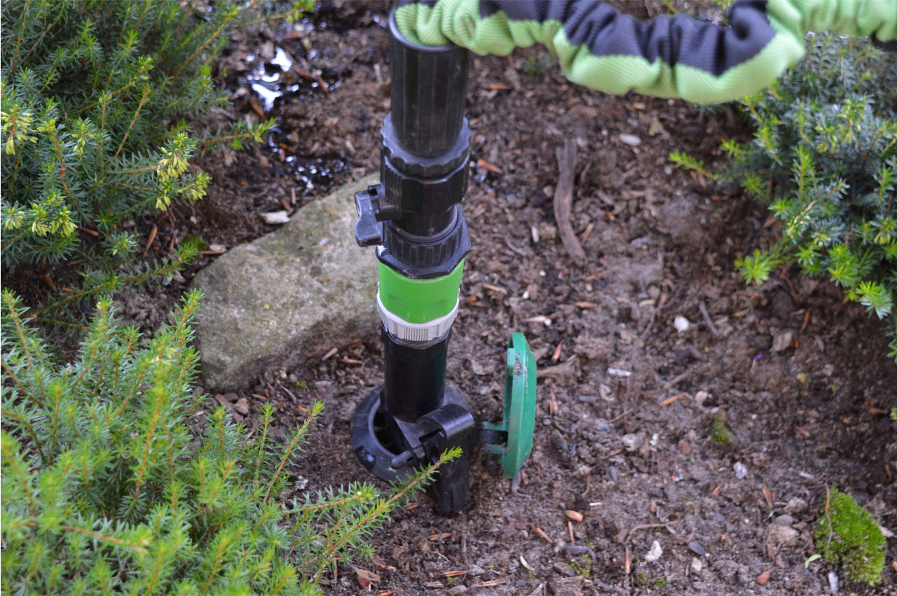 Wassersteckdose betriebsbereit mit angeschlossenen Gartenschlauch